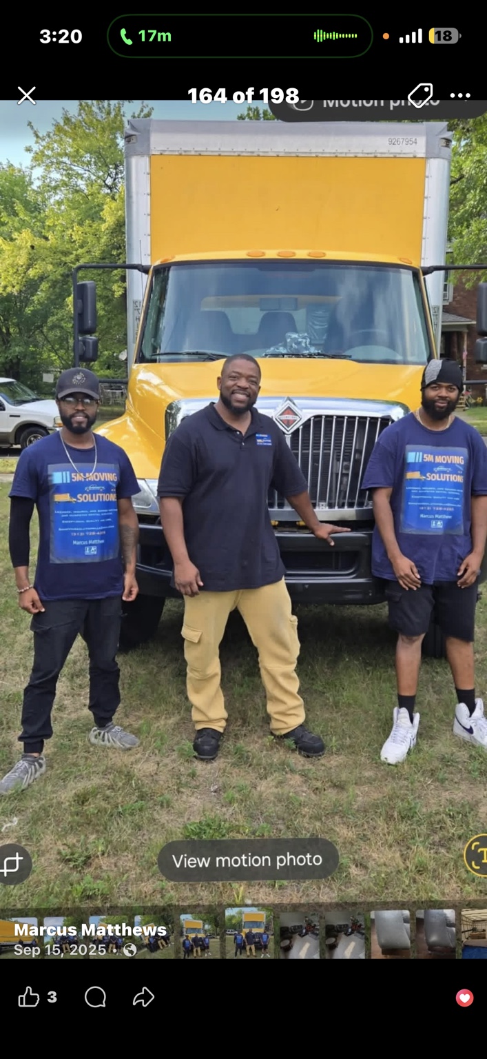 Three 5M team members standing in front of their yellow moving truck