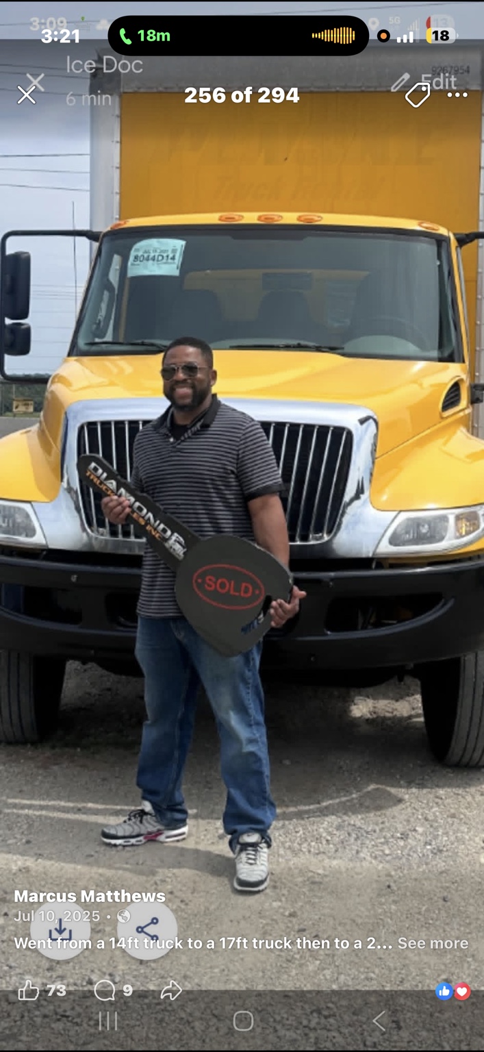 A man holding a sold key in front of a yellow moving truck